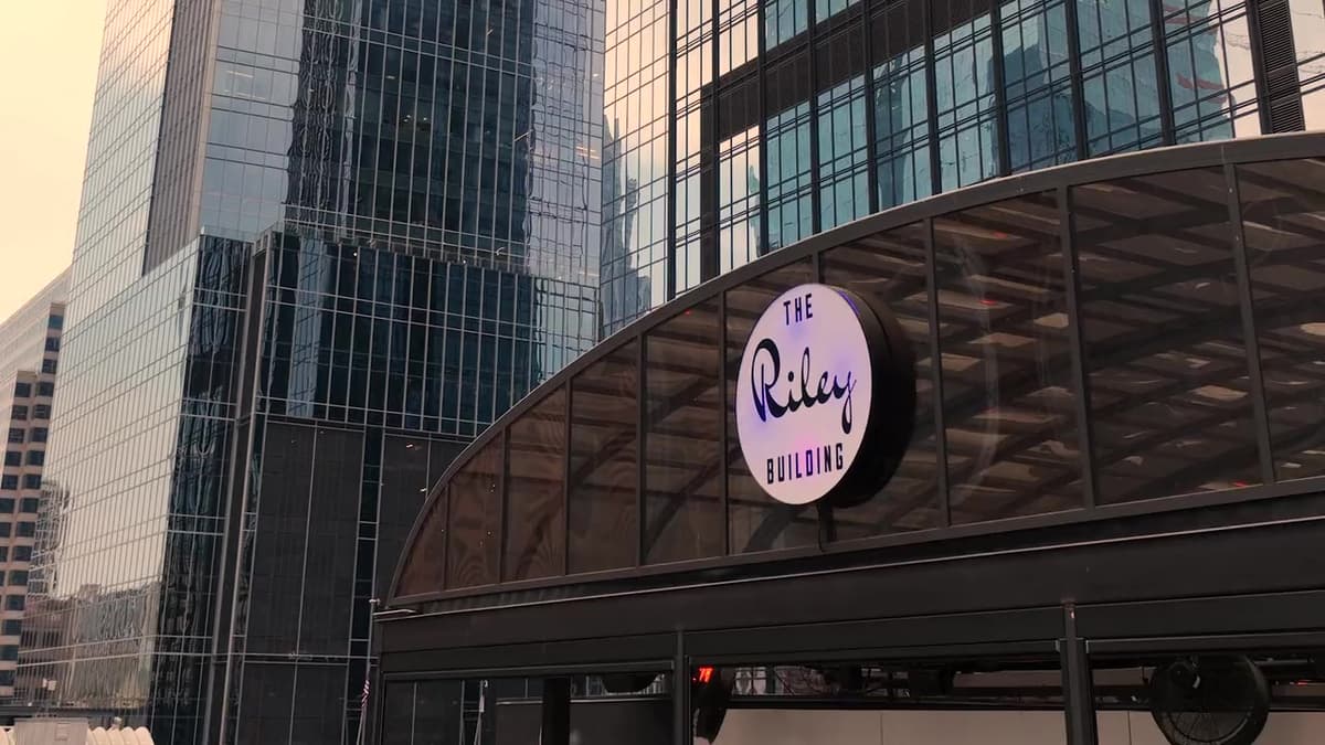 Patron El Cielo Austin film still. The Riley Building sign against downtown glass.