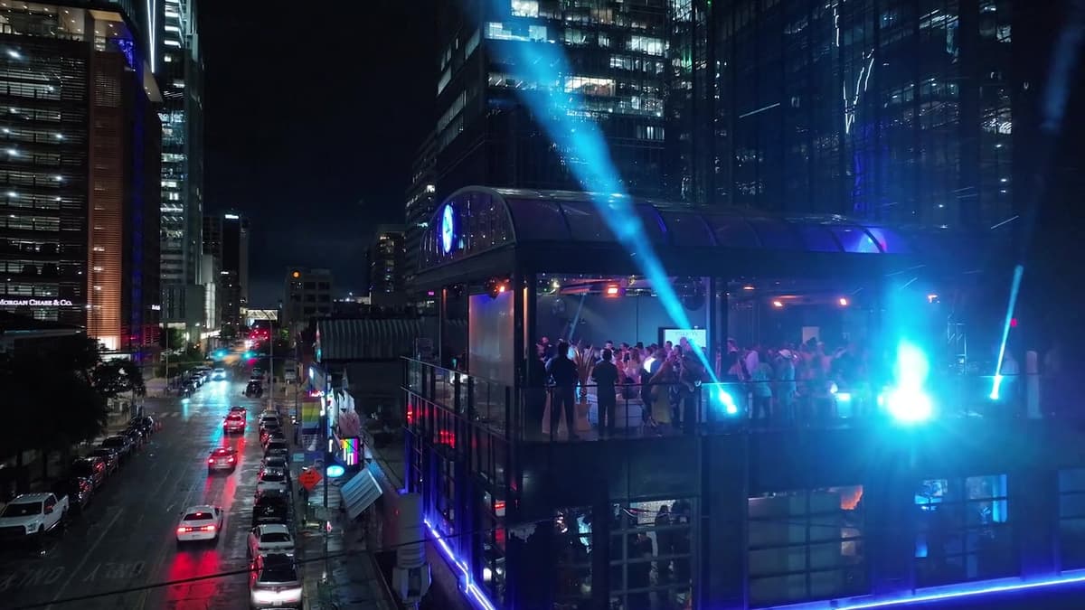 Patron El Cielo Austin film still. Blue-lit rooftop over a wet downtown street.
