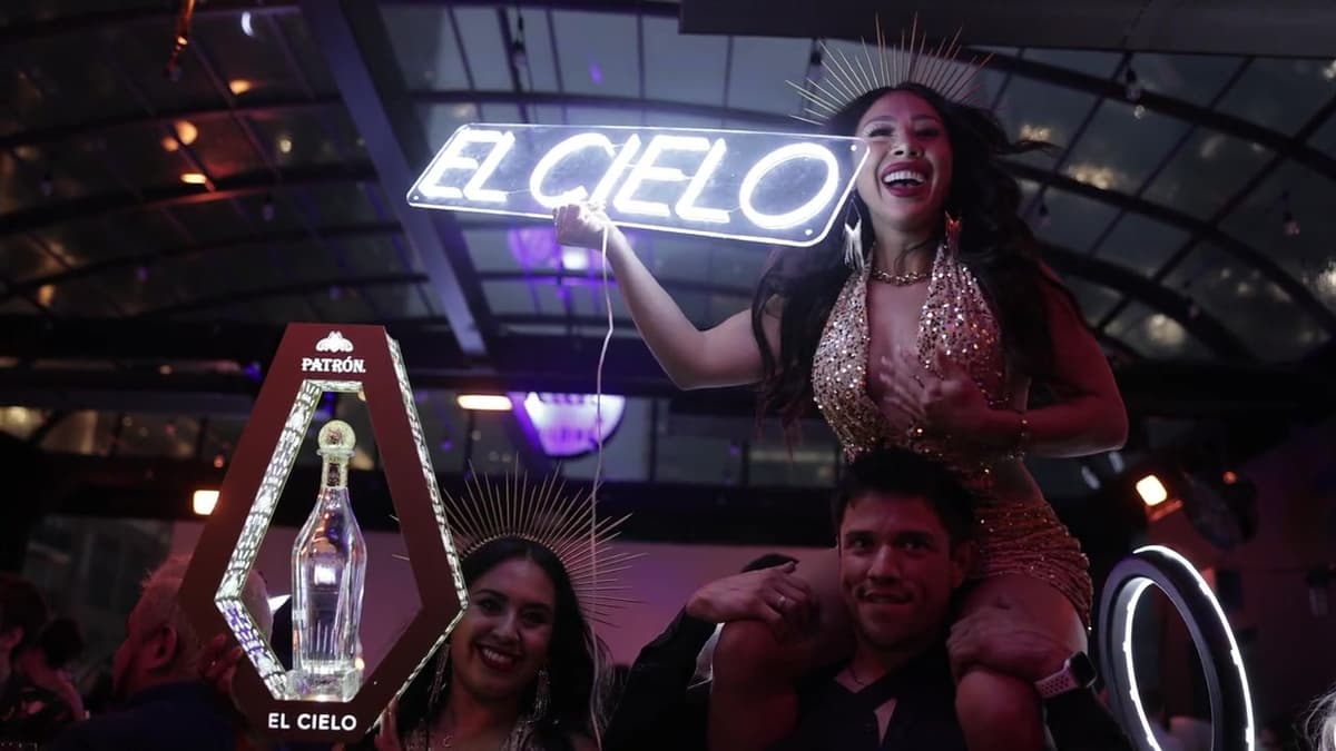 Patron El Cielo Austin film still. A guest holds an El Cielo neon sign from someone's shoulders.
