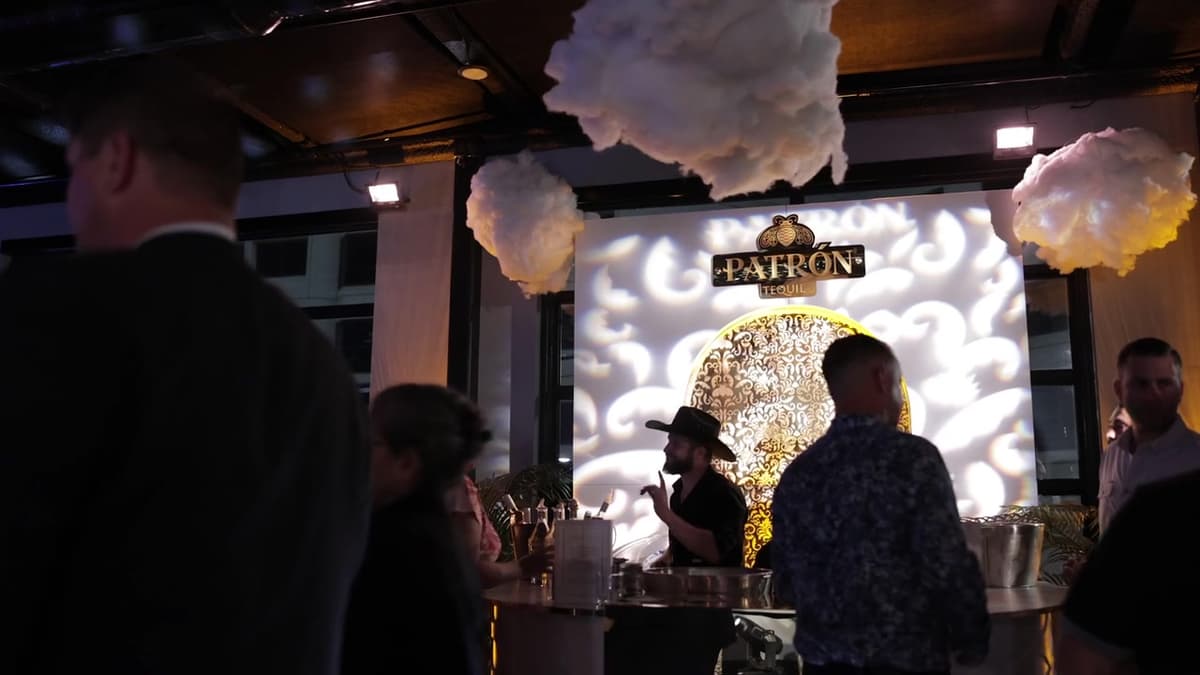 Patron El Cielo Austin film still. Cloud hangings, Patron Tequila mark, and a bartender in a wide hat.