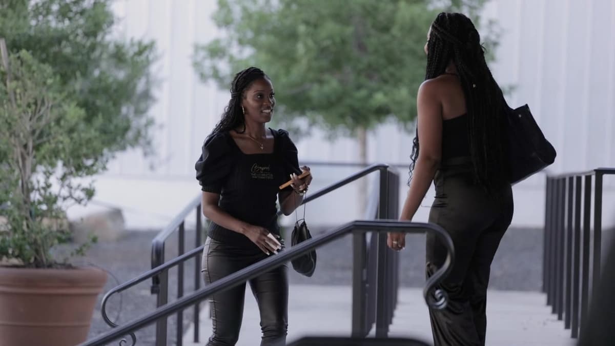 Patron El Cielo Houston film still. Two guests meet on a walkway in daylight.